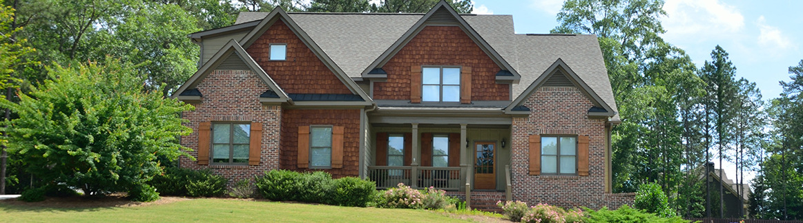 front of a two story house with mature trees around it.