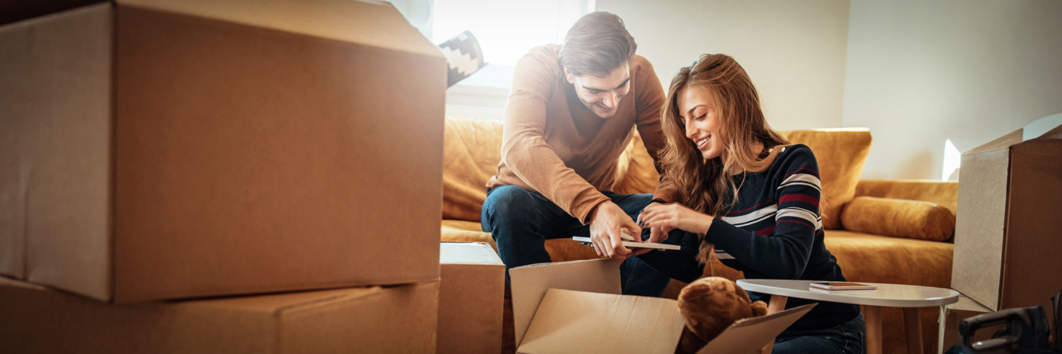 Happy couple unpacking boxes in new home