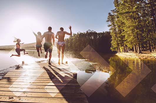 A family running off the end of the dock in to a lake.