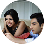 young couple in their home sitting on the couch looking at a comp