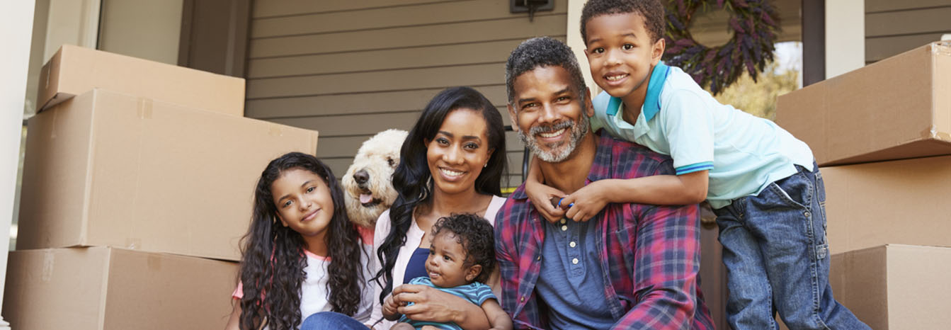 Couple with three young children and moving boxes on porch