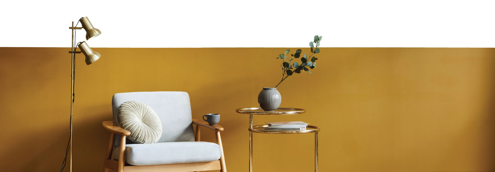 Lamp, chair and table in front of a gold wall