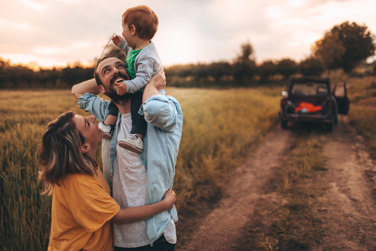 Couple with child on shoulders looking at land for a new home