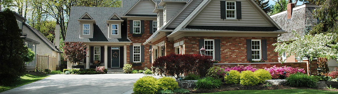 front of a one story house with a driveway and manicured lawn